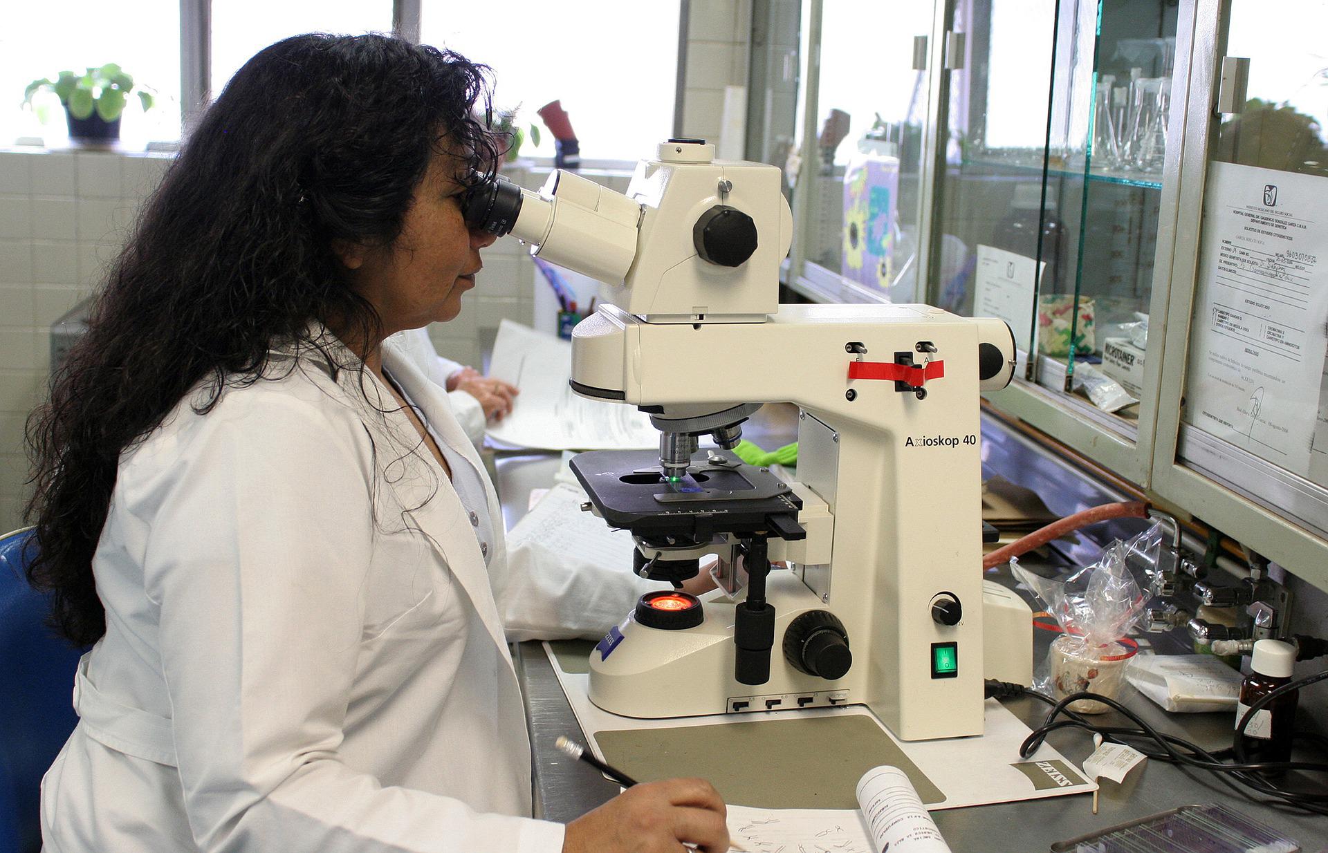 health professional looking through microscope at a laboratory sample